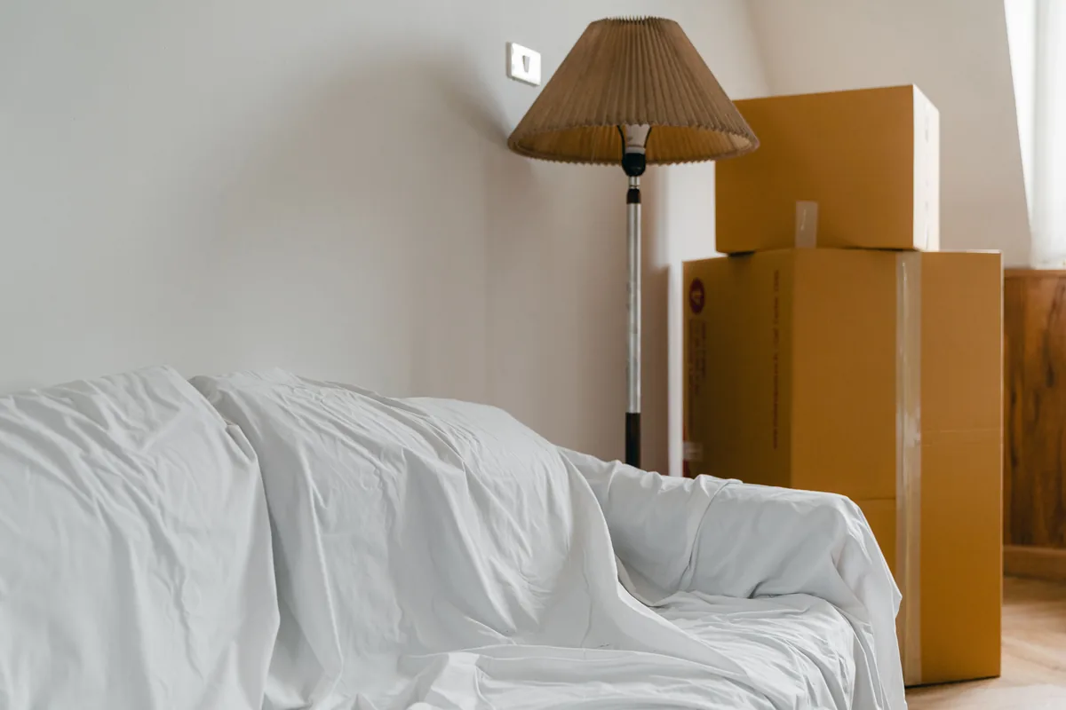 Canapé protégé sous une housse et cartons rassemblés dans un séjour en cours de vidage