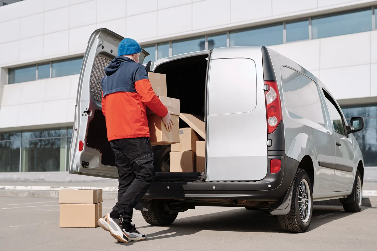 Manutentionnaire chargeant des cartons à l'arrière d'un utilitaire