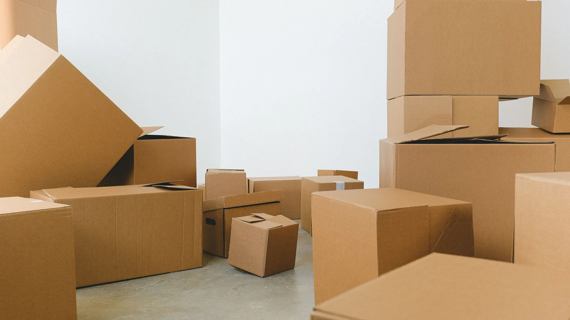 Cartons de déménagement empilés dans une pièce vidée aux murs blancs